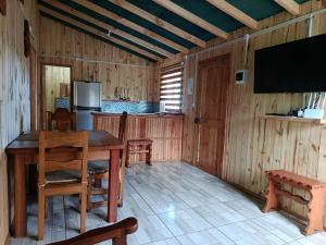 a dining room with a table and a flat screen tv at cabaña zoila ch in Coñaripe