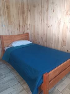 a bed in a room with a wooden wall at cabaña zoila ch in Coñaripe