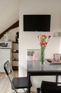 a vase of flowers on a table with a television at Le Relais de Louis in Orbigny +10 photos