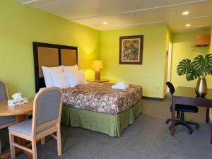 a hotel room with a bed and a table and a desk at Grand Persepolis Inn in Niagara Falls +15 photos