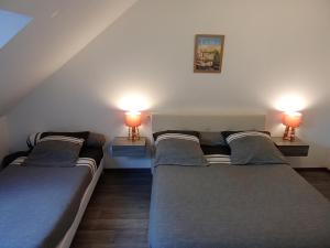 three beds in a room with two lamps on the wall at Le Relais de Jeanne in Orbigny