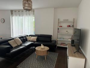 a living room with a black leather couch and a table at Villa Inelda in Saint-Paul