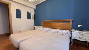 a bedroom with a large bed and a blue wall at Mitxelena in Zarautz +2 photos