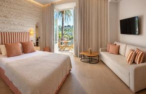 a hotel room with a bed and a couch at La Bastide Du Port - Hôtel de Charme in Saint-Tropez