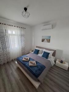 a white bedroom with a large bed with blue pillows at Varanda Encantada House in Ponta do Sol
