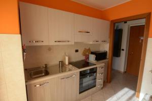 a kitchen with white cabinets and an orange wall at Casa Verena in Aosta +3 photos