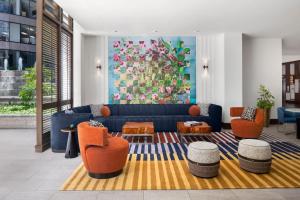 a living room with a blue couch and orange chairs at The Westshore Grand, Tampa, A Tribute Portfolio Hotel in Tampa