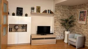 a living room with a television on a cabinet and a chair at Mitxelena in Zarautz