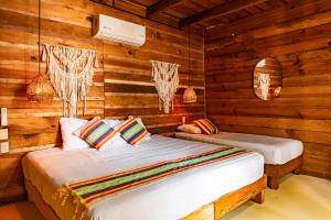 a bedroom with two beds in a log cabin at Straw hat suites La punta in Santa María Colotepec