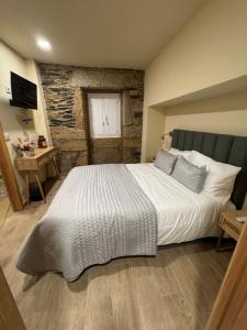 a bedroom with a large bed with a stone wall at Casa da Prima in Torre de Moncorvo