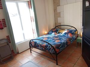 a bedroom with a bed with a floral bedspread at Le Relais du Jardin in Orbigny