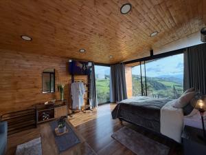 a bedroom with a bed and a large window at Cabañas El Abuelo in La Calera