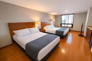 a hotel room with two beds and a television at Hotel Estelar Suites Jones in Bogotá