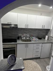 a kitchen with white cabinets and a clock on a counter at Apt Amor in Bihać