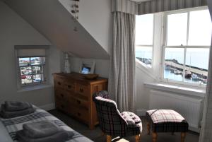 a bedroom with a bed and two chairs and a window at Harbourside Apartment in Anstruther