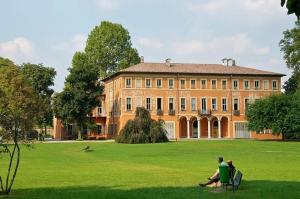 two people sitting on a bench in front of a large building at Suite in Private Villa in Milan