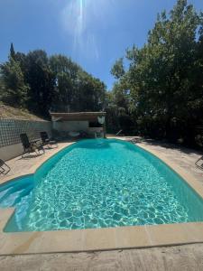 a large blue pool with two chairs and trees at Bastide de Valvérane in Manosque