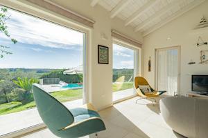 a living room with a large window and chairs at Villa dei Gruccioni - YourPlace Abruzzo in Torino di Sangro