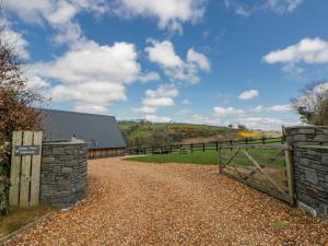 a gate on a dirt road next to a barn at Valley View Hideaway in Llandysul
