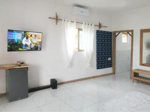 a white room with a tv on a wall at Duna Serena Tiny Houses in Praia do Tofo