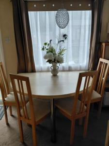 a dining room table with a vase of flowers on it at Holiday Home in Forfar