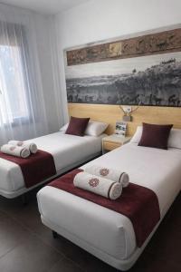 two beds in a hotel room with towels on them at El Mensario in Campisábalos