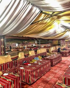 a tent with tables and chairs in a room at Sand Rose Camp - Wadi Rum in Wadi Rum