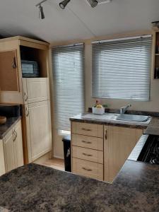 a kitchen with a sink and a counter with windows at Holiday Home in Forfar