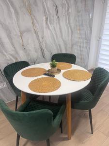 a table with four green chairs and a white table with a table at Fresh Time Apartment in Kecskemét