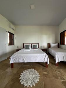 a bedroom with two beds with white sheets on them at Pousada Recanto da Mãezinha in Beberibe