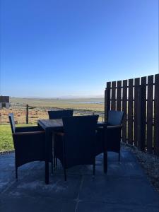 a table and chairs on a patio with a fence at Millfield Glamping Pods - Heatherhouse in Orkney