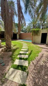 a pathway leading to a house with a palm tree at مجموعة سدرة فاطمة in Al Ahsa