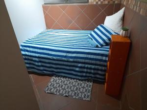 a small bed with a blue and white striped blanket at Stadion Sleepover Cabin in Sasolburg