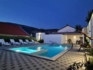a swimming pool with chairs in a backyard at night at Holiday Home with Private Pool in Blagaj