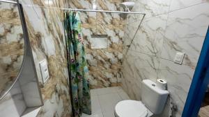 a bathroom with a shower and a toilet in it at Vale das Rainhas Pousada Santo Amaro BA in Santo Amaro