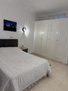 a bedroom with a white bed and a white cabinet at Résidence central 1 in Nabeul +1 photo
