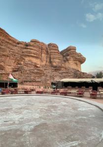 a table and chairs in front of a rock wall at Sand Rose Camp - Wadi Rum in Wadi Rum