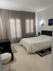 a bedroom with a bed and a window with curtains at Résidence central 1 in Nabeul