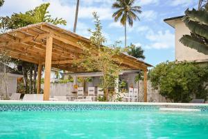 a swimming pool with a pergola and a house at Hostel La Bohème in Las Terrenas