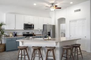 a kitchen with white cabinets and a kitchen island with bar stools at Gorgeous Lakefront Paradise w Pool & Views in Chandler
