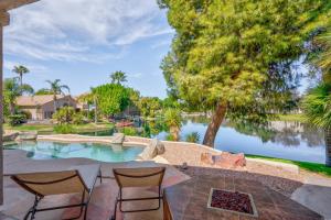 a patio with two chairs and a pool with trees and water at Gorgeous Lakefront Paradise w Pool & Views in Chandler