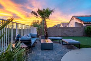 a patio with couches and a palm tree and a sunset at Heated Pool 3BR Retreat Estrella Mountain in Goodyear