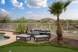 a patio with a couch and a palm tree at Heated Pool 3BR Retreat Estrella Mountain in Goodyear