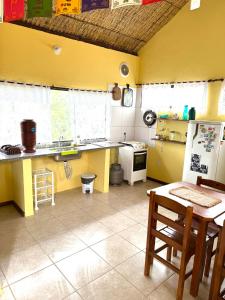a kitchen with yellow walls and a table and a refrigerator at Loft com vista Panoramica in Paraty