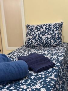 a bed with blue and white floral sheets and pillows at Centro de Alfenas Térreo Completo in Alfenas