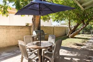 a table with four chairs and an umbrella at Charming 2-BR Farmhouse Backyard Views in Mesa