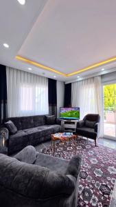 a living room with couches and a flat screen tv at PRETTY HOUSE in Pamukkale