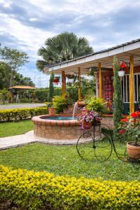a house with a fountain in the grass with flowers at Finca Campestre Villa del Campo in Santa Rosa de Cabal