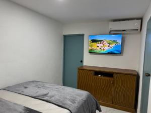 a bedroom with a bed and a tv on the wall at Arubaapartamentos in Oranjestad
