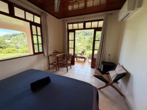 a bedroom with a bed and a desk and windows at Villa Ura in Uturoa